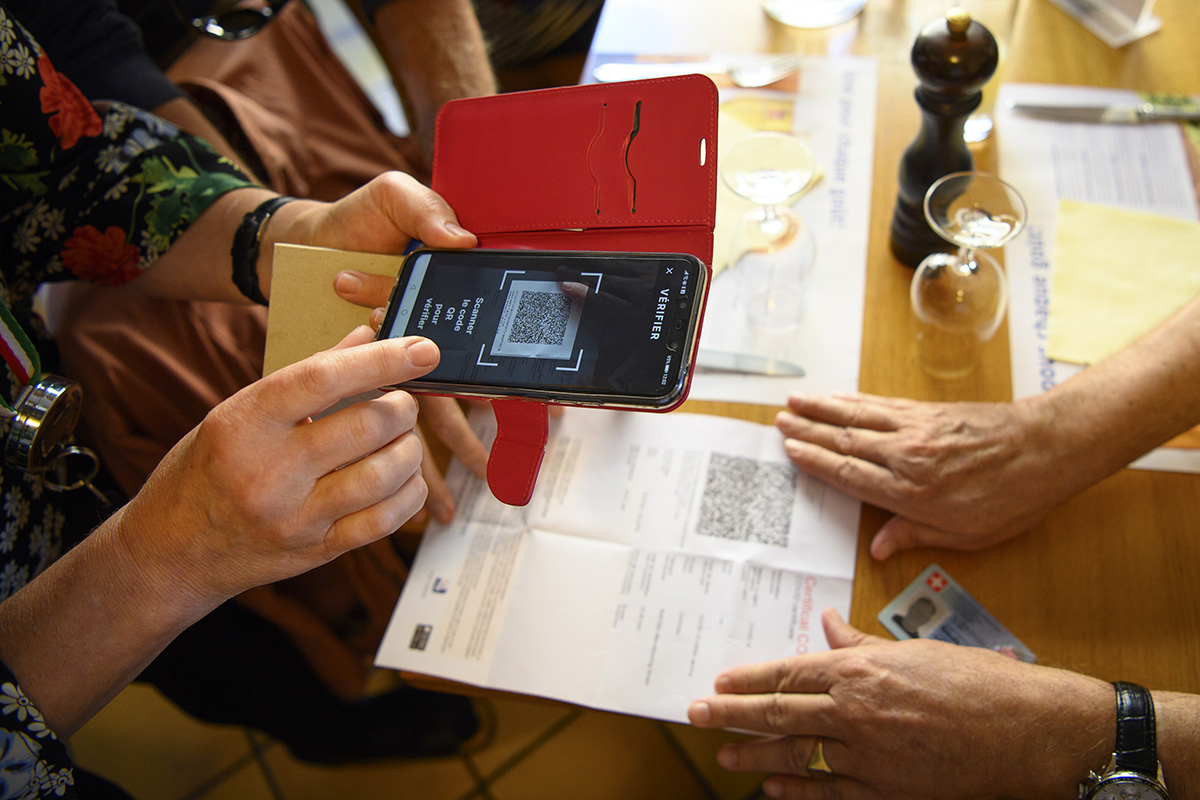 Eine Kellnerin prüft am 13. September 2021 im Café-Restaurant L'Europe in Lausanne mit einem Smartphone das COVID-Zertifikat eines Kunden. Seit dem 13. September 2021 gilt national die vom Bundesrat beschlossene erweiterte Zertifikatspflicht. Foto: Keystone-SDA / Laurent Gilliéron
