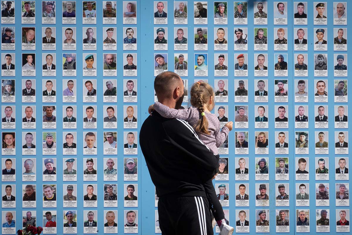 Ein Mann betrachtet am 8. September 2022 in Kiev zusammen mit seiner Tochter die Gedenkwand für gefallene ukrainische Soldaten im russisch-ukrainischen Krieg. Soldaten müssen in der Ukraine für den Kriegseinsatz das Erwachsenenalter erreicht haben. Foto: Keystone-SDA / AP Photo, Efrem Lukatsky
