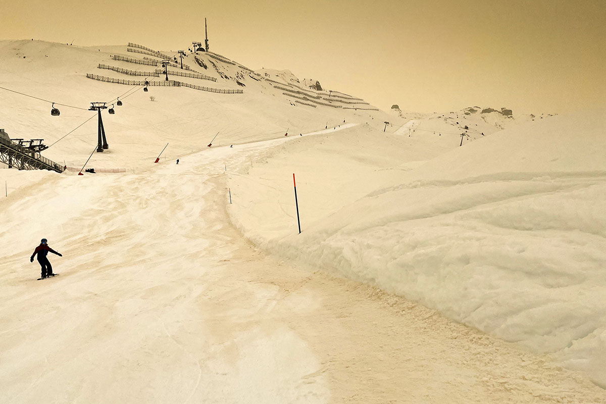 Saharasand färbt den  Schnee und den Himmel am 6. Februar 2021 in ein orangenes Licht, hier auf einer Piste des Schweizer Alpenressort Anzère. Foto: Keystone-SDA/Laurent Gilliéron