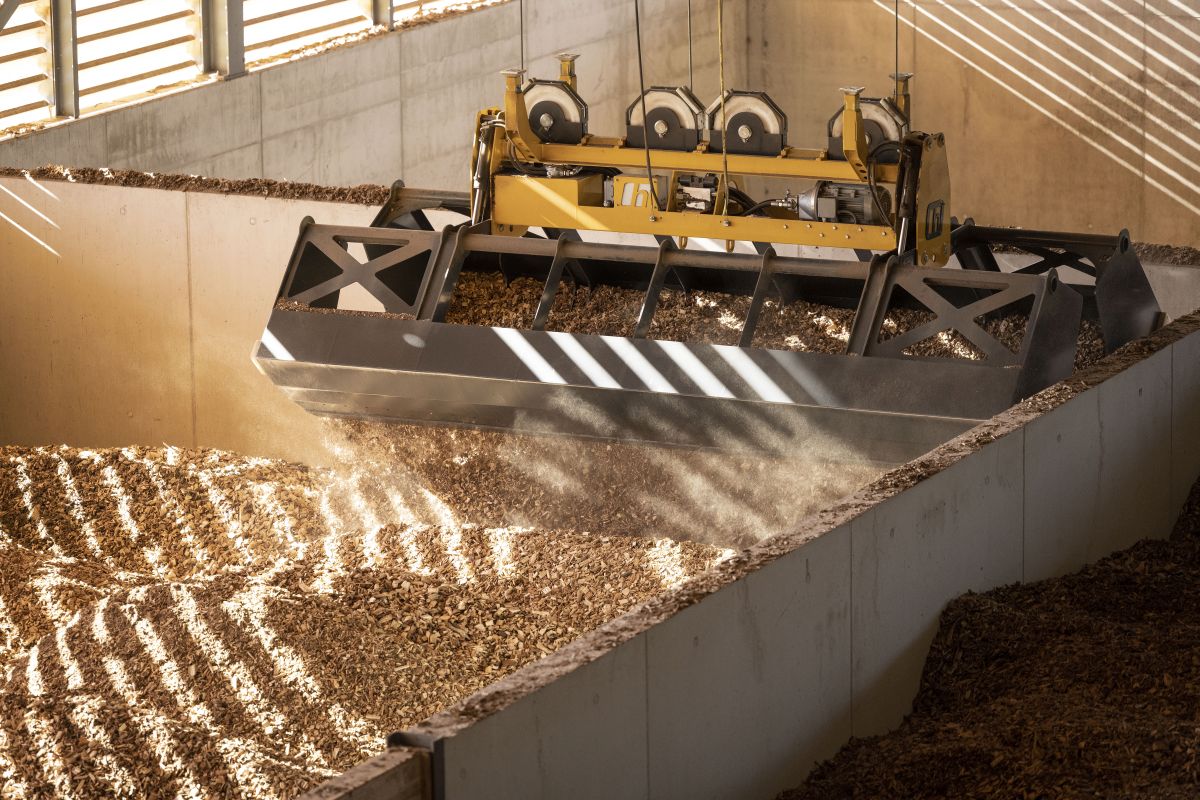 529791866 – Ein Kran schaufelt am 13. Juli 2022 die Holzschnitzel in die verschiedenen Trocknungsboxen im Holzheizkraftwerk der Bioenergie Frauenfeld. Foto: KEYSTONE / Christian Beutler