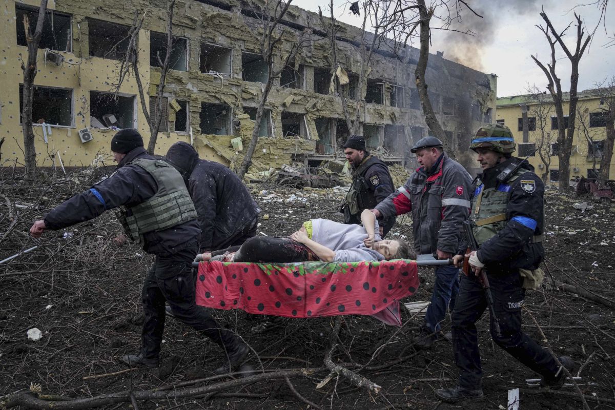 511135845 - Des sauveteurs et des volontaires ukrainiens transportent une femme enceinte blessée hors de la maternité de Marioupol endommagée par des tirs russes, le 9 mars 2022. Photo : KEYSTONE/ AP Photo/ Evgeniy Maloletka