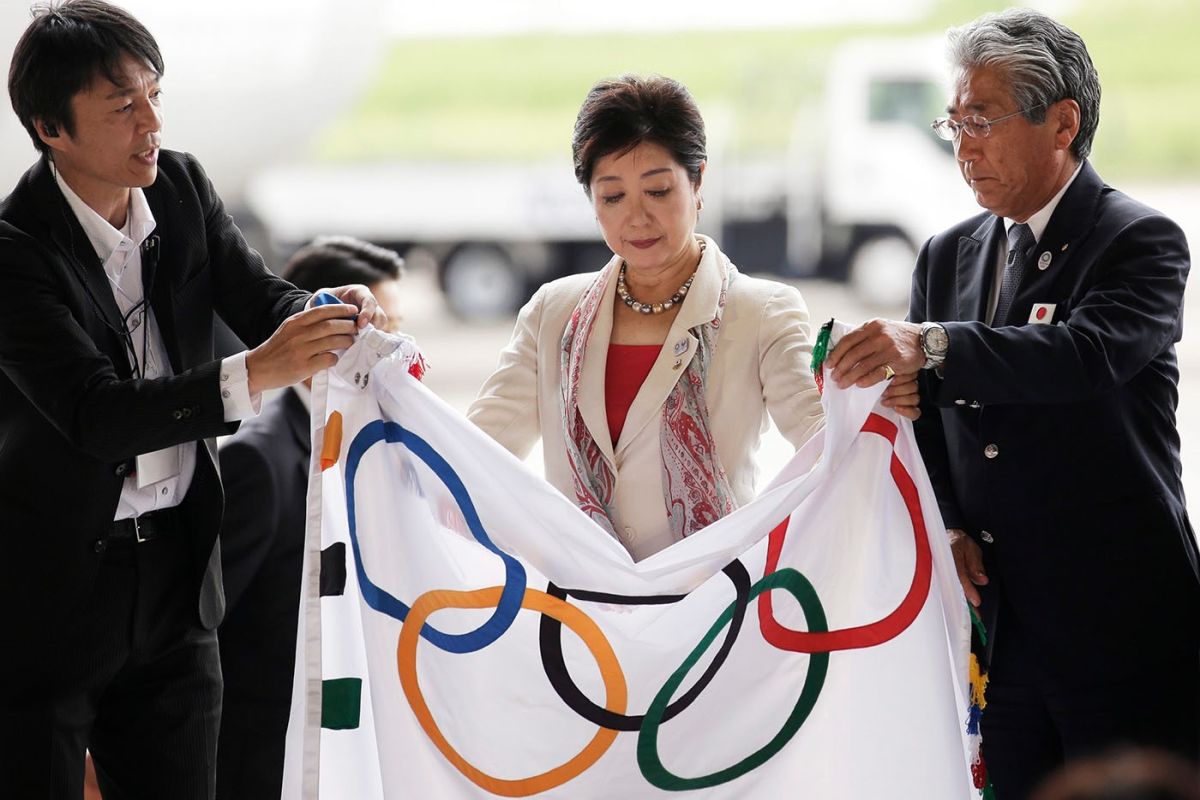 Die Gouverneurin von Tokio, Yuriko Koike (Mitte), entrollt die olympische Flagge mit dem Präsidenten des Japanischen Olympischen Komitees (JOC), Tsunekazu Takeda (rechts), am 24. August 2016 während der Zeremonie der Ankunft der olympischen Flagge in Tokio. Foto: epa/ Kiyoshi Ota